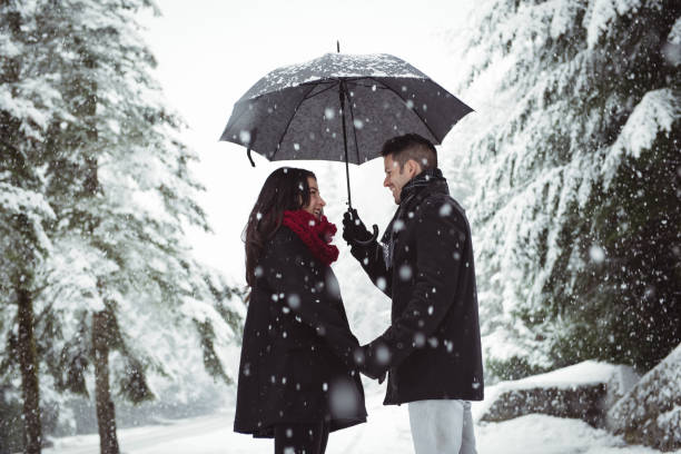 istock Smiling couple under umbrella standing in forest 657679256