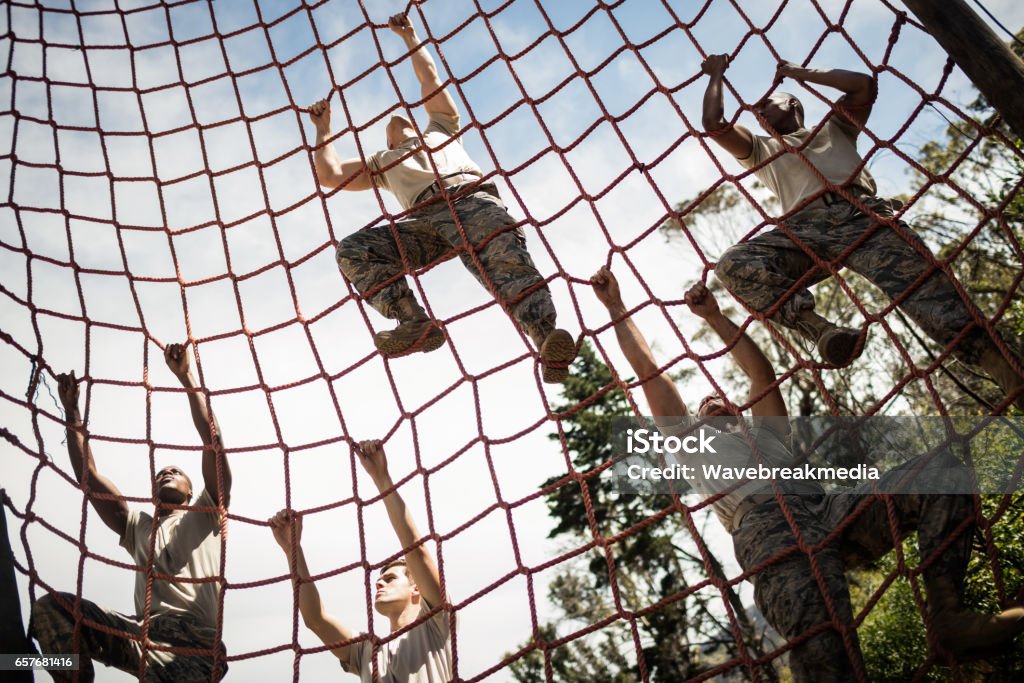 Military soldiers climbing rope during obstacle course Military soldiers climbing rope during obstacle course in boot camp Military Training Stock Photo