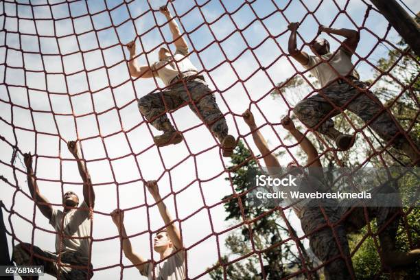 Military Soldiers Climbing Rope During Obstacle Course Stock Photo - Download Image Now