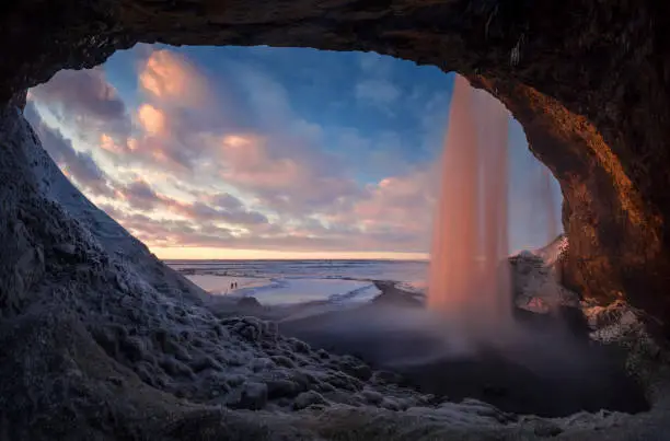 Colorful sunset in cave behind Seljalandsfoss waterfall in winter, Iceland