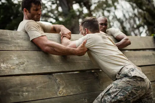 Photo of Soldiers helping man to climb wooden wall