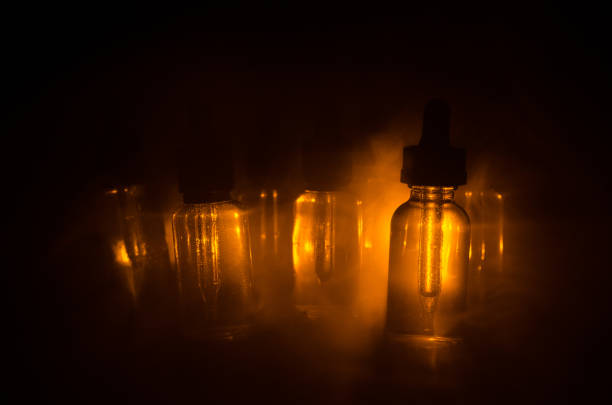 istock Vape concept. Smoke clouds and vape liquid bottles on dark background. Light effects. Useful as background or vape advertisement. 657688754
