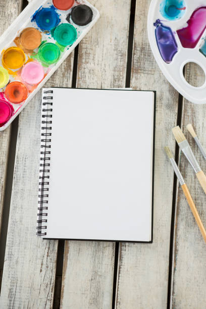 istock Colorful palette, paintbrushes and blank book on wooden surface 657688856