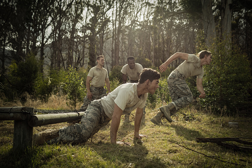 Soldiers crawling under the net during obstacle course in boot camp