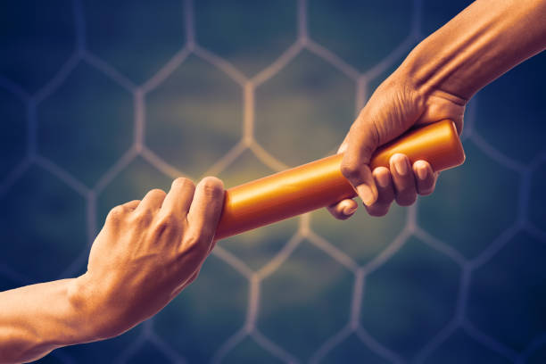 hands passing a relay baton on on soccer goal net background with vintage color tone effect. stock photo