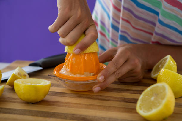 istock Woman preparing lemon juice from juicer against violet background 657737490
