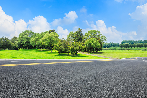Asphalt road and green trees landscape in the blue sky