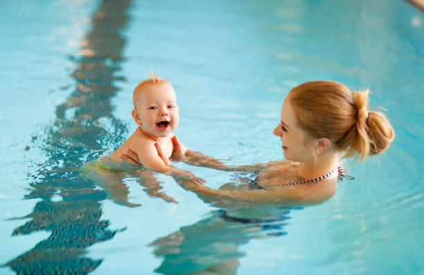 madre y bebé nadan en piscina - bebe bañandose fotografías e imágenes de stock
