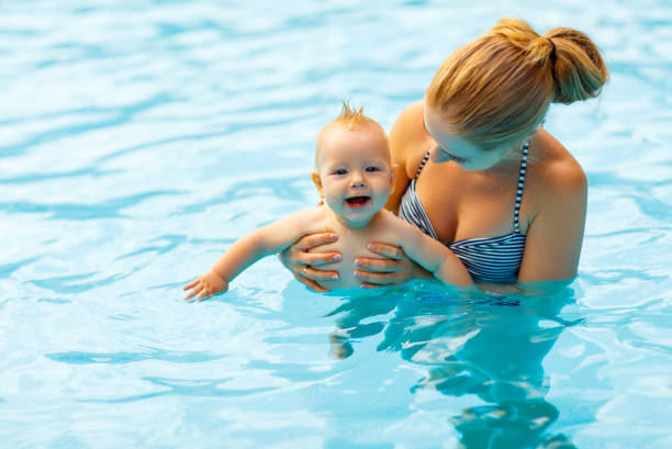 mother and baby swim  in pool - blue water swimming pool sports and fitness imagens e fotografias de stock