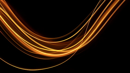 A long exposure photo of gold fairy lights, in a curve from left to right, against a clean black background