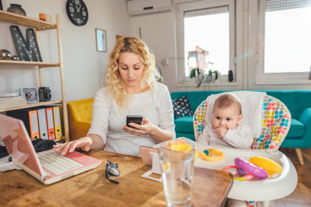 istock Mother using smart phone at home office with her baby 657768550