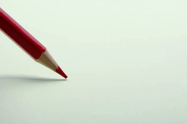 Red pencil is drawing on the blank background.