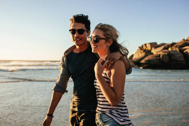 istock Young happy couple walking on seashore and smiling. 657794022