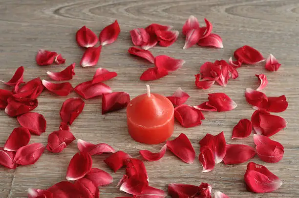 A red candle with red rose petals