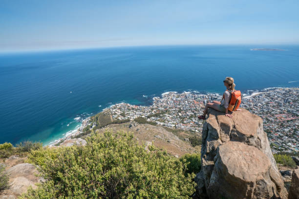 молодая женщина в кейптауне на вершине горы, глядя на вид - lions head mountain стоковые фото и изображения