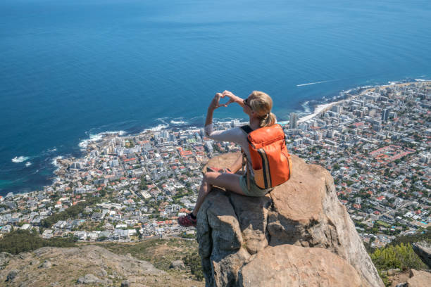 istock Young woman on mountain top making heart shape with hands 657795440