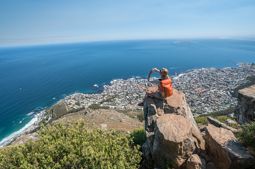 Young woman on top of mountain in Cape Town making a heart shape finger frame. Love environment travel people concept. Shot on top of Lion's head famous mountain in South Africa.