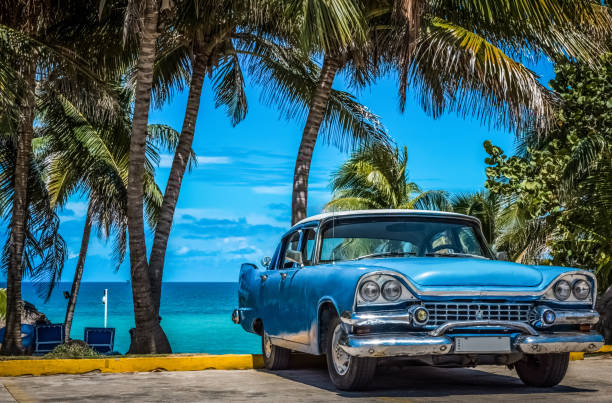 American blue vintage car parked under palms in Varadero Cuba stock photo
