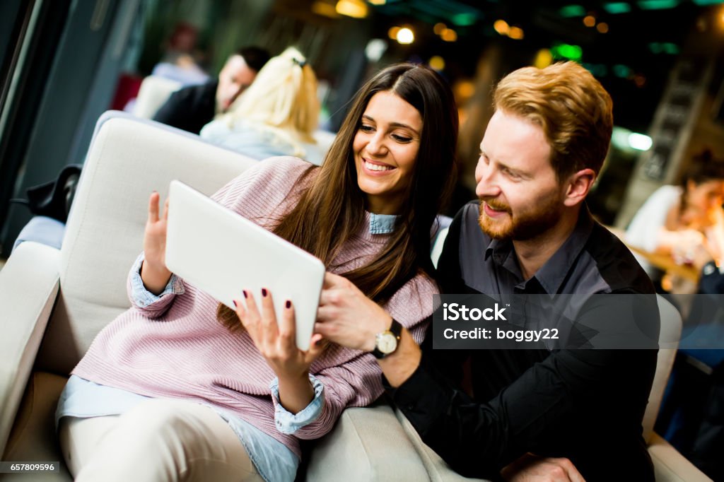 Young modern couple sitting together and using a tablet View at young modern couple sitting together and using a tablet 20-29 Years Stock Photo