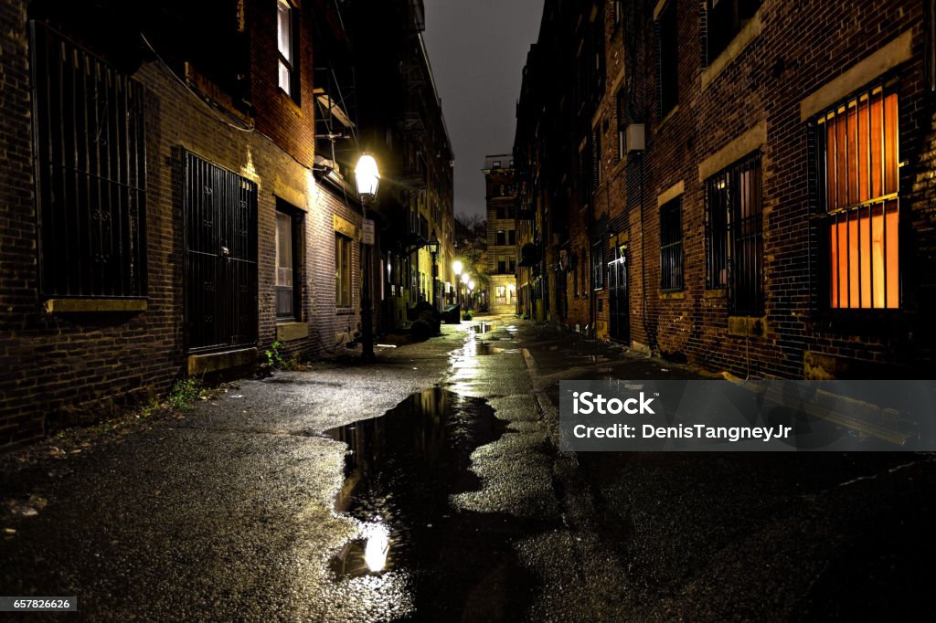 Long dark urban alley between two old buildings Long dark alley between two old buildings in the North End neighborhood of Boston at night Alley Stock Photo