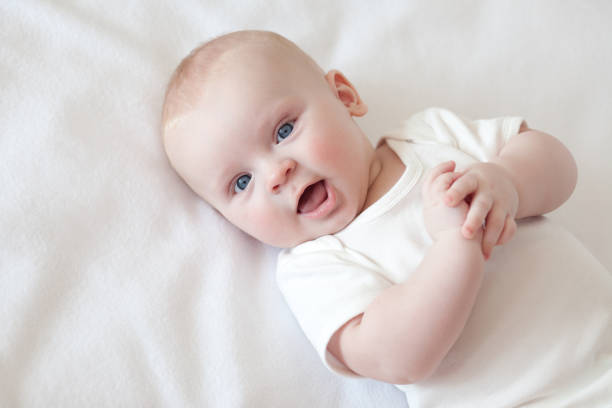 smiling baby in white clothes lays