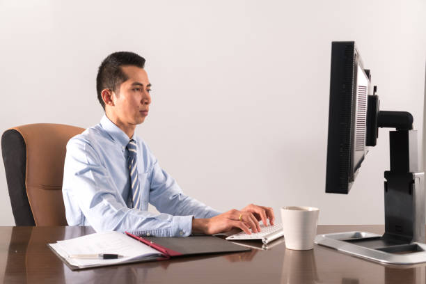 istock Vietnamese business man sitting at desk typing on computer keyboard 657833208