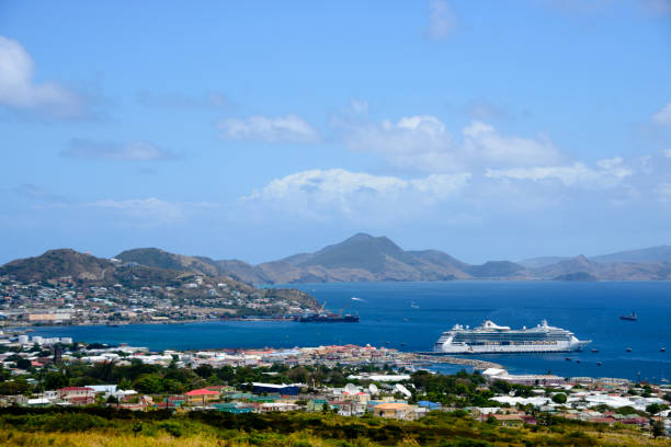 Scenic view over the city of Basseterre, the capital city of Saint Kitts and Nevis.  The mountain of the island of Nevis can be seen in the background. A cruise ship is docked in Basseterre Bay.