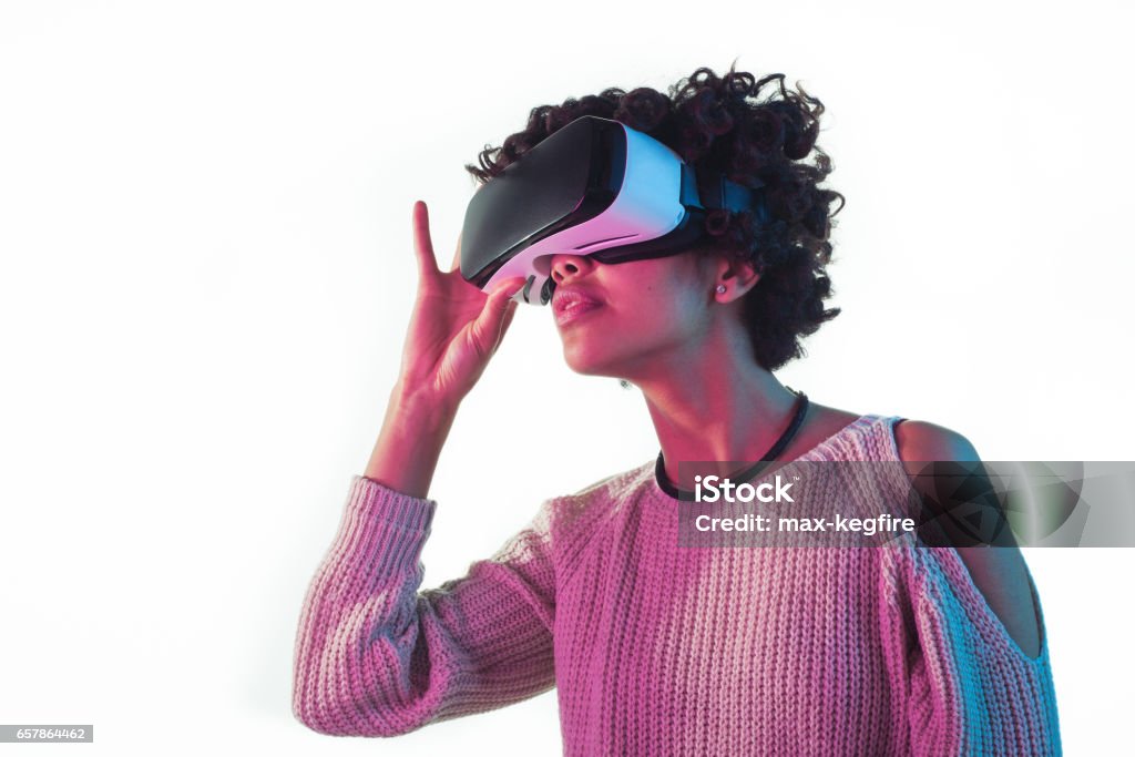 Woman adjusting VR goggles Young woman touching the virtual reality glasses standing on the white background. Virtual Reality Stock Photo