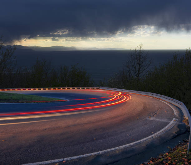 istock Car lights at night by the sea 657867934