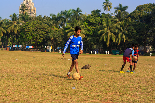 A kid playing football at local football stadium located at South Mumbai, India