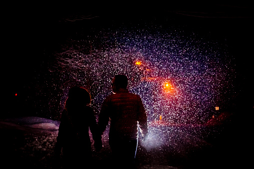 A couple walks on a snowy road during a snowstorm in a country village. Saint-Hugues, Quebec.
