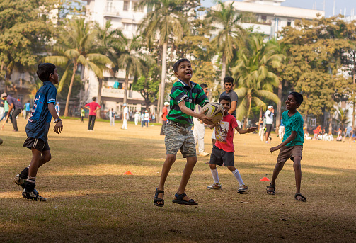 Group of children playing football at local football stadium located at South Mumbai, India