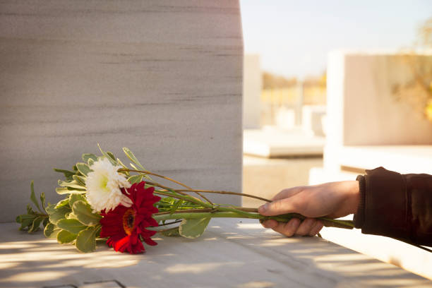 istock Hand holding flowers on tombstone 657894020
