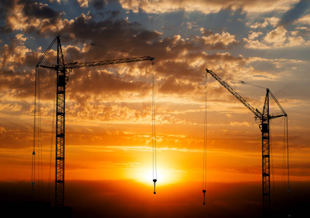 istock Hoisting cranes working on beautiful cloudy sky with orange sunset 657913750