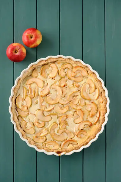 Apple tart with whole apples on turquoise stripped background vertical