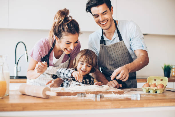 mama und papa machen cookies zu helfen - two parent family indoors home interior domestic kitchen stock-fotos und bilder