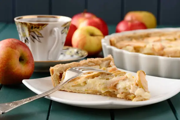 Apple tart with cup of tea and whole apples closeup
