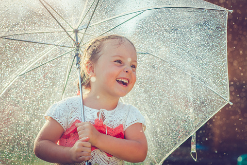 Little girl having fun in rain in summer
