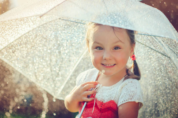 Little girl having fun in rain in summer
