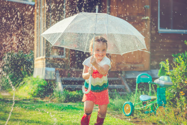 Little girl having fun in rain in summer