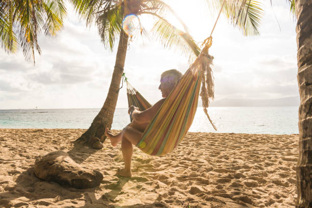 uomo anziano in amaca sulla spiaggia - hammock beach vacations tropical climate foto e immagini stock