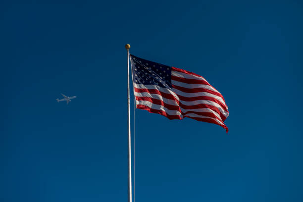 istock Low angle view of waving American flag with moving airplane 657949182