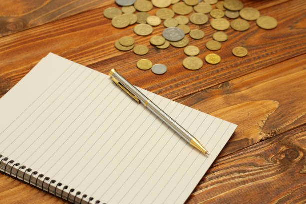 istock paper notebook with pen and coins on whood background 657961928