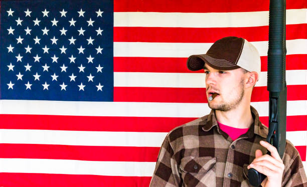istock Young Man Holding Gun on American Flag Background 657966062