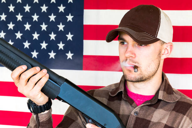 istock Young Man Holding Gun on American Flag Background 657966078