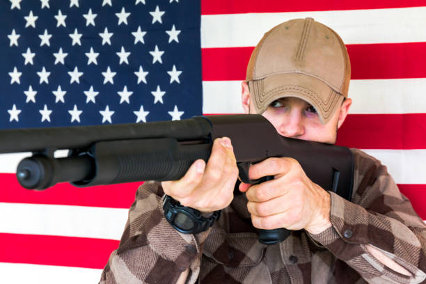 istock Young Man Holding Gun on American Flag Background 657966088