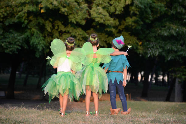 chłopiec w kostiumie i dwie dziewczyny w zielonym kostiumie bajki ze skrzydłami - czarodziejki zdjęcia i obrazy z banku zdjęć