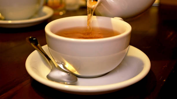 istock Pouring black tea into cup from teapot 657977716