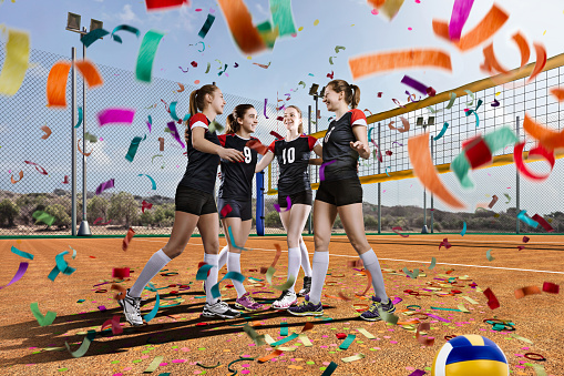 Female volleyball team celebrating victory on volleyball field