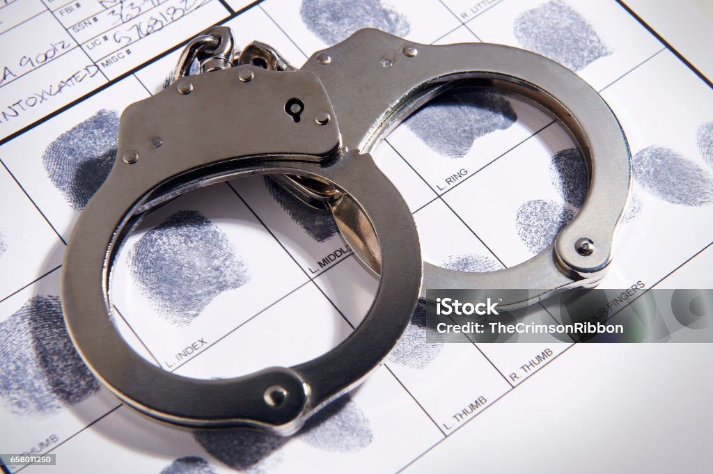 Handcuffs laying on top of fingerprint chart in file Handcuffs Stock Photo